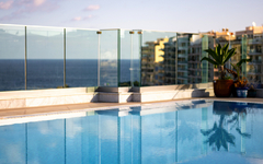 Pool auf Dachterrasse mit Blick aufs Meer und Gebäude im Hintergrund