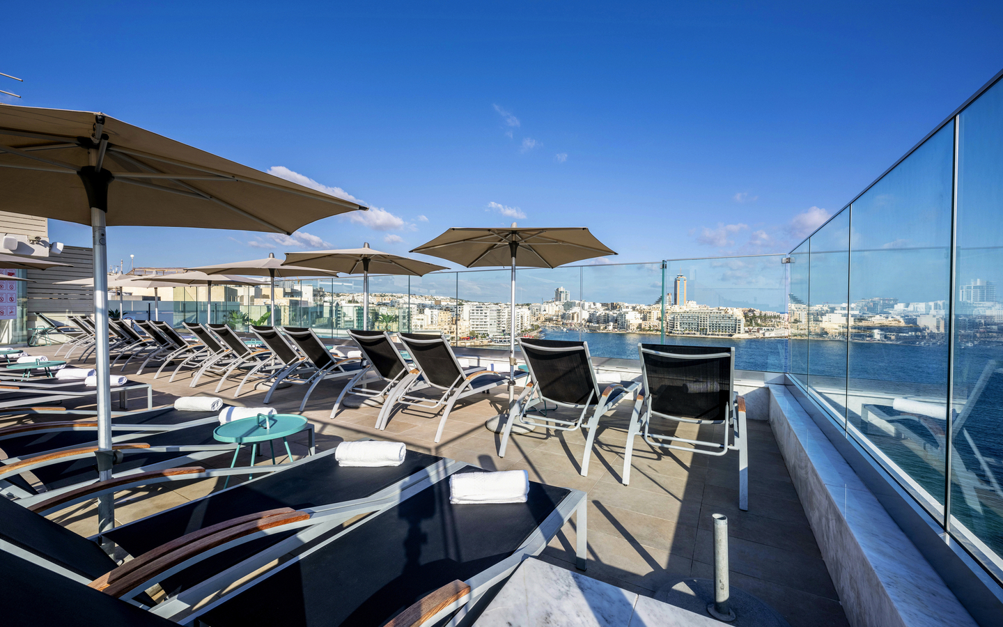 Sonnenterrasse mit Liegestühlen und Blick auf das Meer im Hotel Plaza Regency, Malta