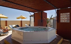 Ein Whirlpool auf einer Hotelterrasse mit Sonnenliegen und Sonnenschirmen.