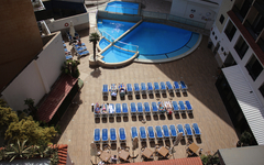 Blick auf Hotelpool mit Liegestühlen und Sonnenschirmen von oben.
