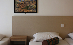 Hotelzimmer mit weißen Betten, blauer Decke und Wandbild.