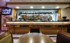 Hotelbar mit Theke, Flaschen im Hintergrund und Tisch im Vordergrund.