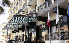Hotelgebäude mit Balkonen und Flaggen vor dem Eingang