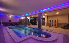 Innenpool im Hotel mit Liegen und blauer Beleuchtung.