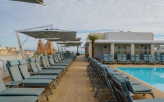 Sonnenliegen und Pool auf der Dachterrasse eines Hotels in Malta bei bewölktem Himmel