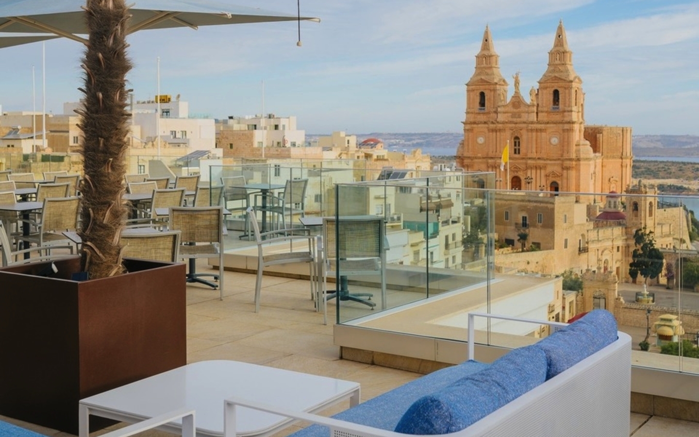 Die Dachterrasse mit Sitzbereichen und Blick auf eine Kirche in Malta.