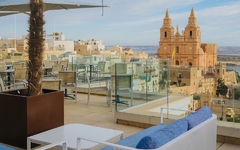 Die Dachterrasse mit Sitzbereichen und Blick auf eine Kirche in Malta.
