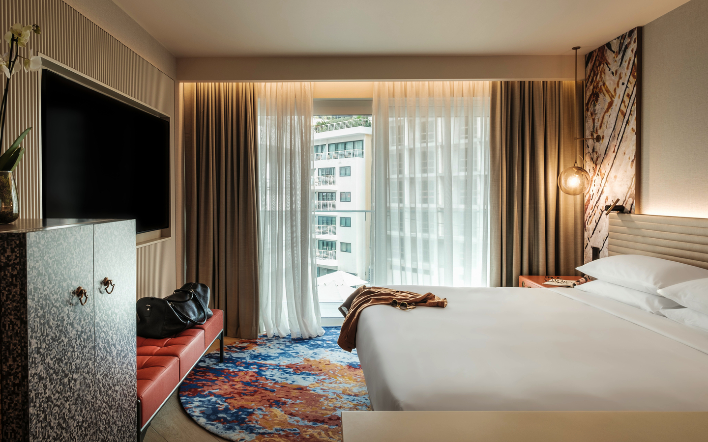 Modernes Hotelzimmer mit großem Bett, Teppich und Fensteransicht.