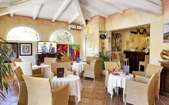 Helle Hotel-Lounge mit Korbmöbeln, Kunstwerken und Barbereich.
