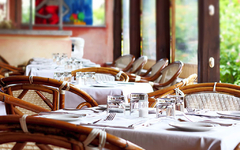 Restaurant mit gedeckten Tischen und Korbstühlen in einem offenen Raum.