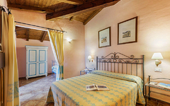 Hotelzimmer mit Doppelbett, Holzbalkendecke und hellen Wänden in warmer Atmosphäre.