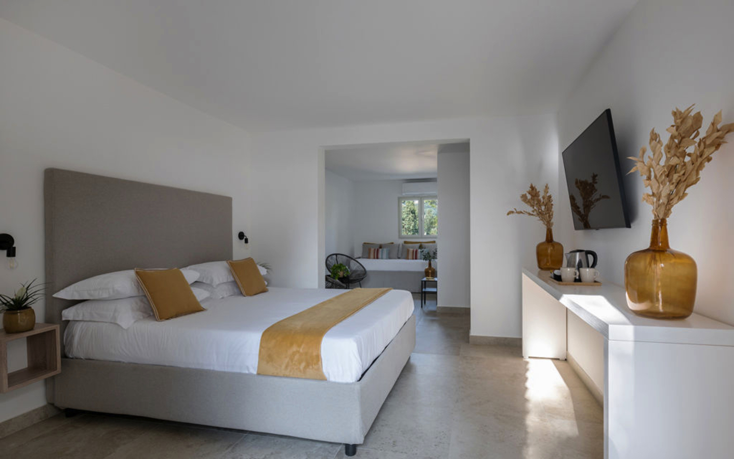 Helles Hotelzimmer mit Doppelbett, Fernseher und Dekoration.