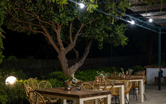Terrasse mit beleuchteten Tischen, Stühlen und Pflanzen bei Nacht.