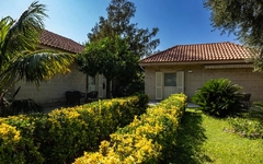 Bungalow im Grünen mit Palmen und Sträuchern unter blauem Himmel.