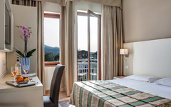 Hotelzimmer mit Doppelbett, Schreibtisch, Fensteraussicht auf Berge und dekorativem Tisch.