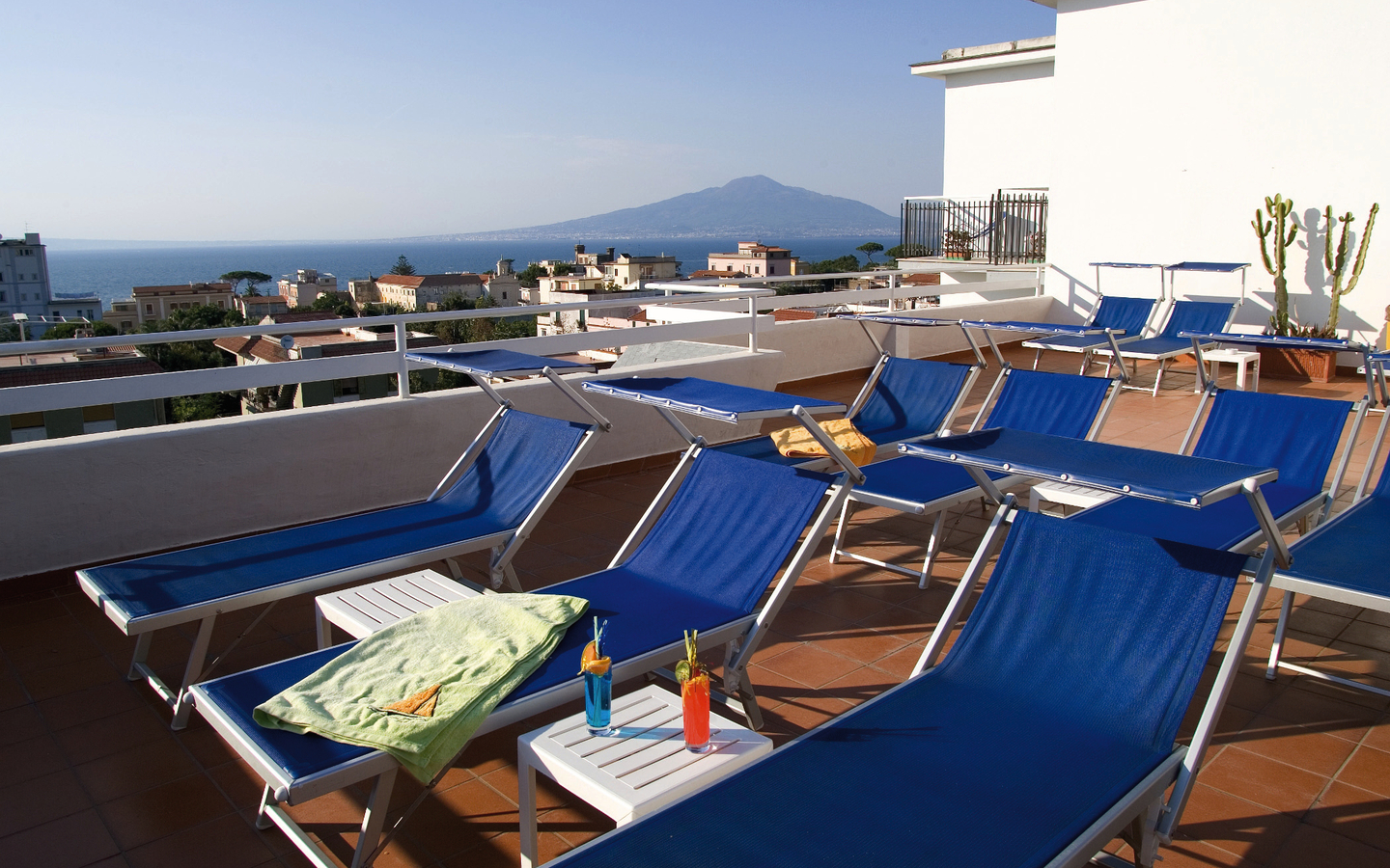 Blauer Himmel und Liegestühle auf der Terrasse mit Blick auf das Meer und Berge.