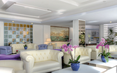 Heller Hotel-Loungebereich mit weißen Sofas und Blumen.