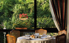 Gedeckter Tisch in einem eleganten Hotelrestaurant mit Blick auf einen grünen Garten.