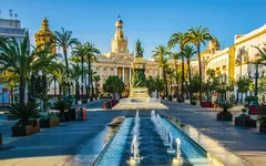 Stadtplatz von Cádiz mit Palmen und Springbrunnen bei sonnigem Wetter.