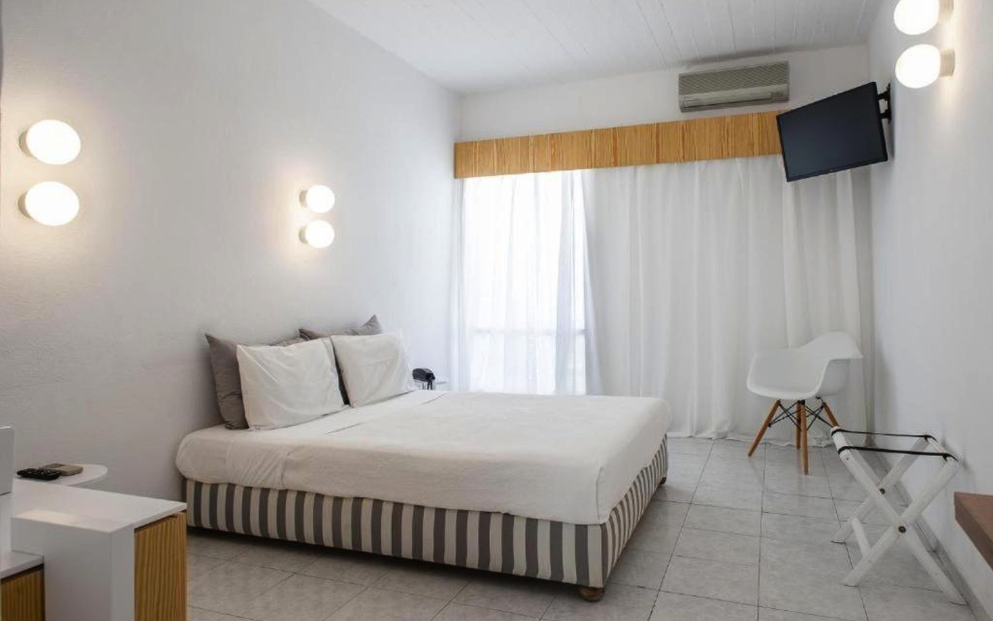 Helles Hotelzimmer mit Doppelbett, weißen Wänden, TV und minimalistischem Dekor.