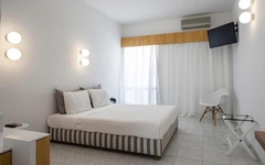 Helles Hotelzimmer mit Doppelbett, weißen Wänden, TV und minimalistischem Dekor.