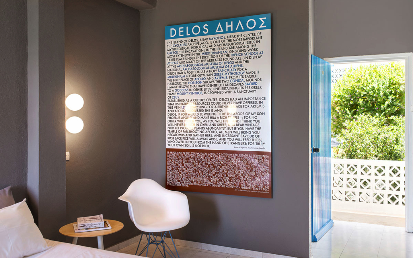 Hotelzimmer mit weißem Stuhl, Wandtext und offener Tür zum Hof