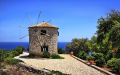 Steinwindmühle auf Zakynthos mit Meerblick und blauem Himmel im Hintergrund