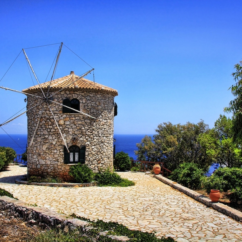 Steinwindmühle auf Zakynthos mit Meerblick und blauem Himmel im Hintergrund