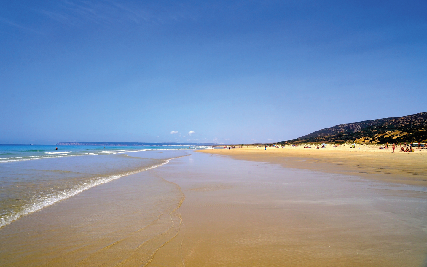 Weitläufiger Sandstrand unter klarem Himmel an der Costa de la Luz in Spanien.