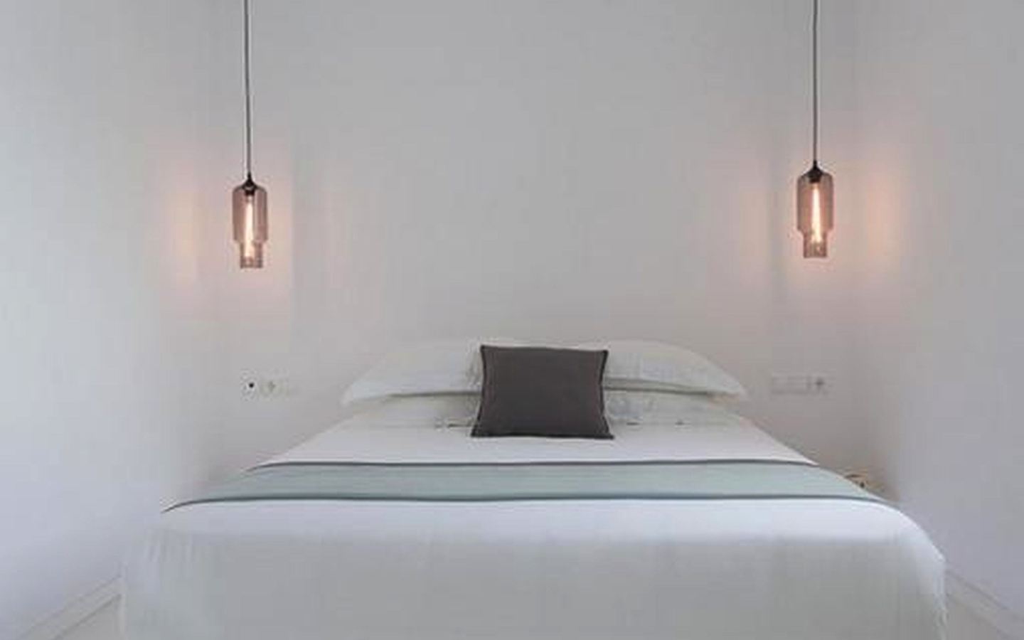 Modernes Hotelzimmer mit weißem Bett und Hängelampen