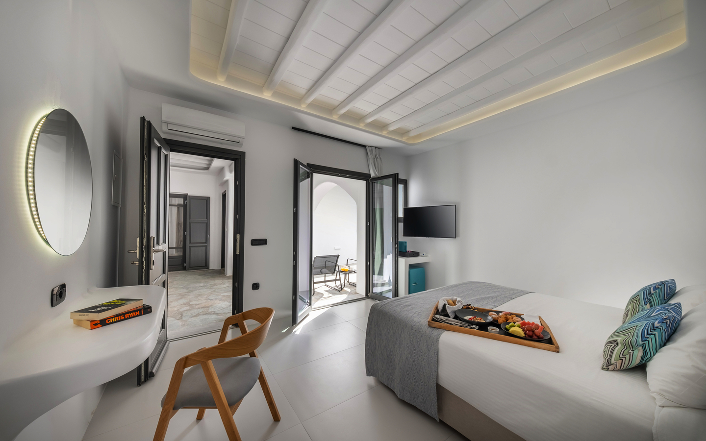 Modernes Hotelzimmer mit Doppelbett, Balkon und Tisch mit Obstplatte.
