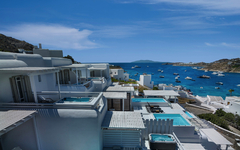 Hotel mit weißen Gebäuden und Pools, Blick aufs Meer und Boote, Mykonos, Griechenland.