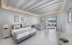 Helles Hotelzimmer mit zwei Betten, Blick auf Mykonos von Balkon.