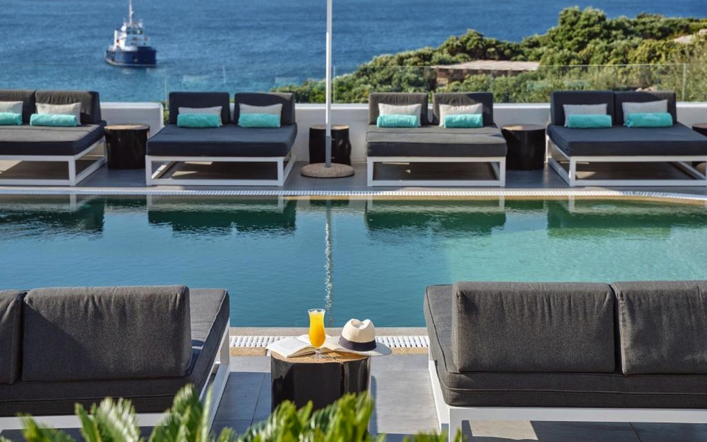 Pool mit Liegen am Mykonos Princess Hotel, Meerblick im Hintergrund.