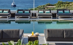 Pool mit Liegen am Mykonos Princess Hotel, Meerblick im Hintergrund.
