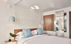 Helles Hotelzimmer mit Doppelbett, blauen Kissen und modernem Dekor.