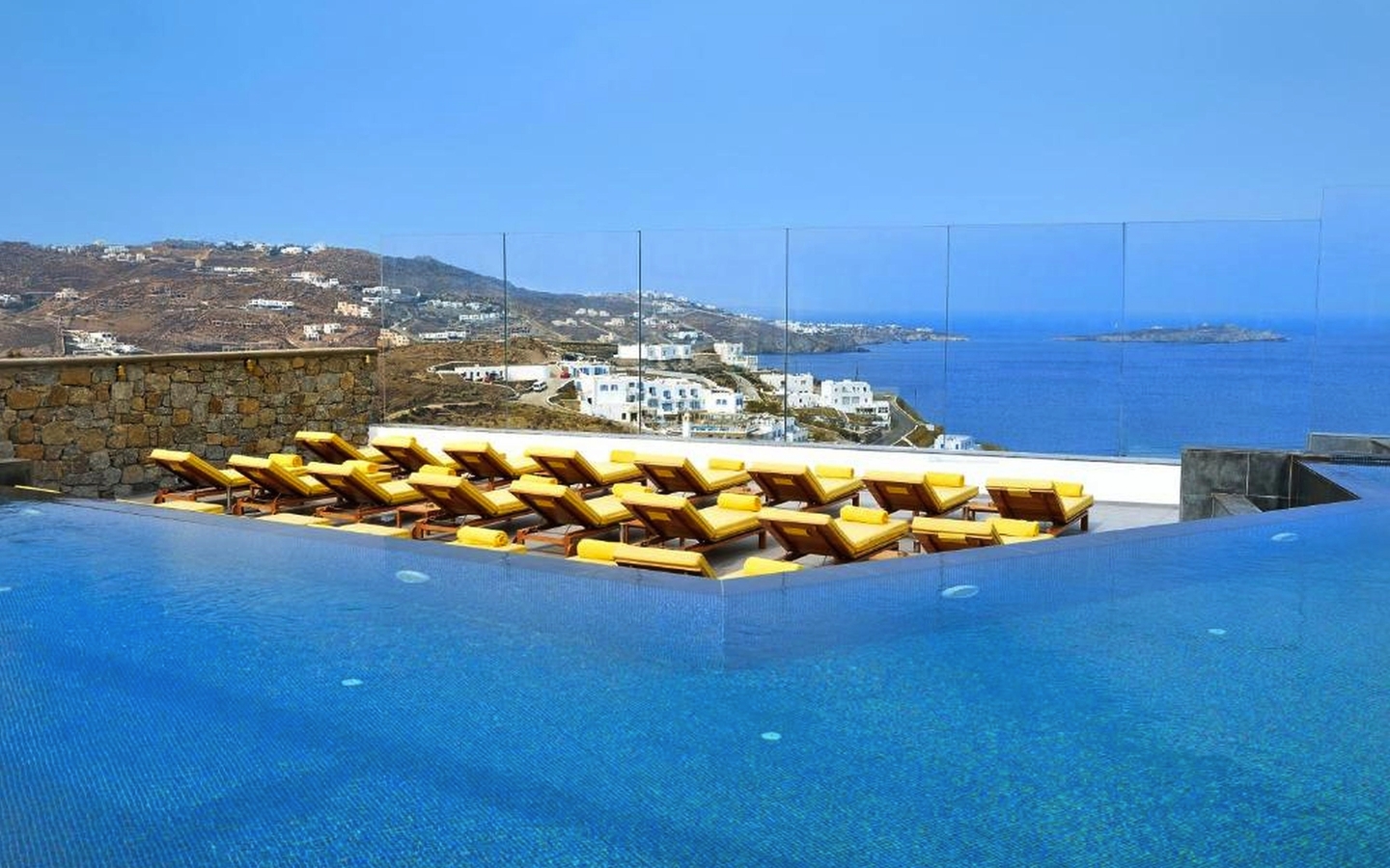 Infinity-Pool mit Liegestühlen und Blick auf das Meer in Mykonos.