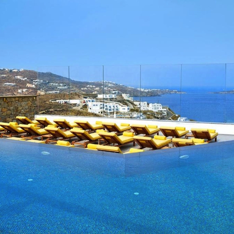 Infinity-Pool mit Liegestühlen und Blick auf das Meer in Mykonos.