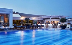 Pool mit Terrasse und Bar im Hotel Myconian Korali auf Mykonos bei Abenddämmerung.