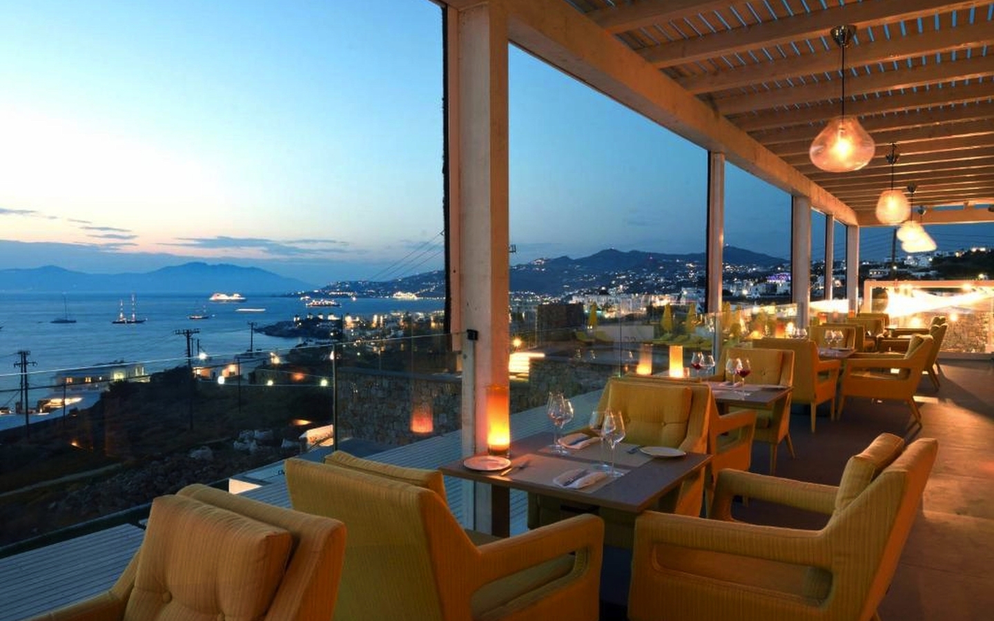 Restaurant mit Meerblick bei Dämmerung, stilvoll eingerichtet mit gedeckten Tischen.