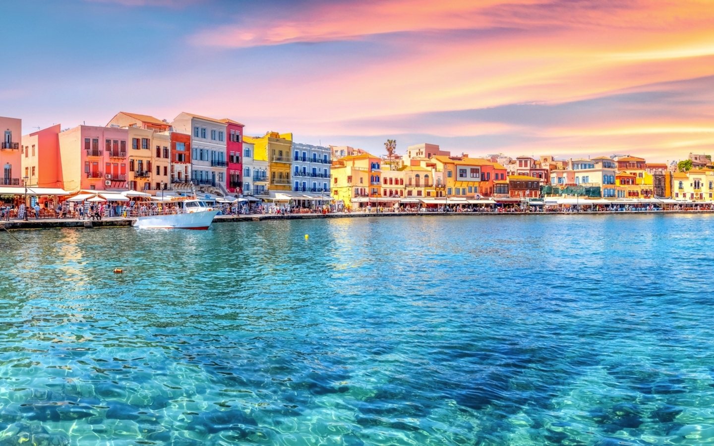 Traditioneller Hafen von Chania, Kreta bei Sonnenuntergang mit bunten Gebäuden.
