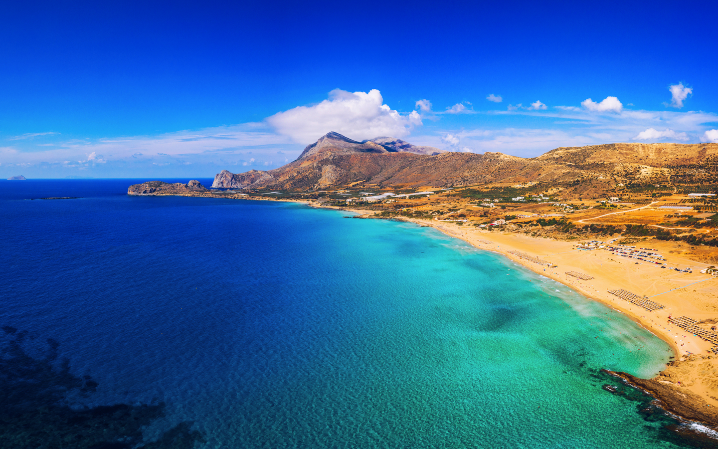 Strand von Falasarna auf Kreta, Griechenland, mit klarem blauem Wasser und Hügel im Hintergrund.