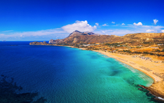 Strand von Falasarna auf Kreta, Griechenland, mit klarem blauem Wasser und Hügel im Hintergrund.