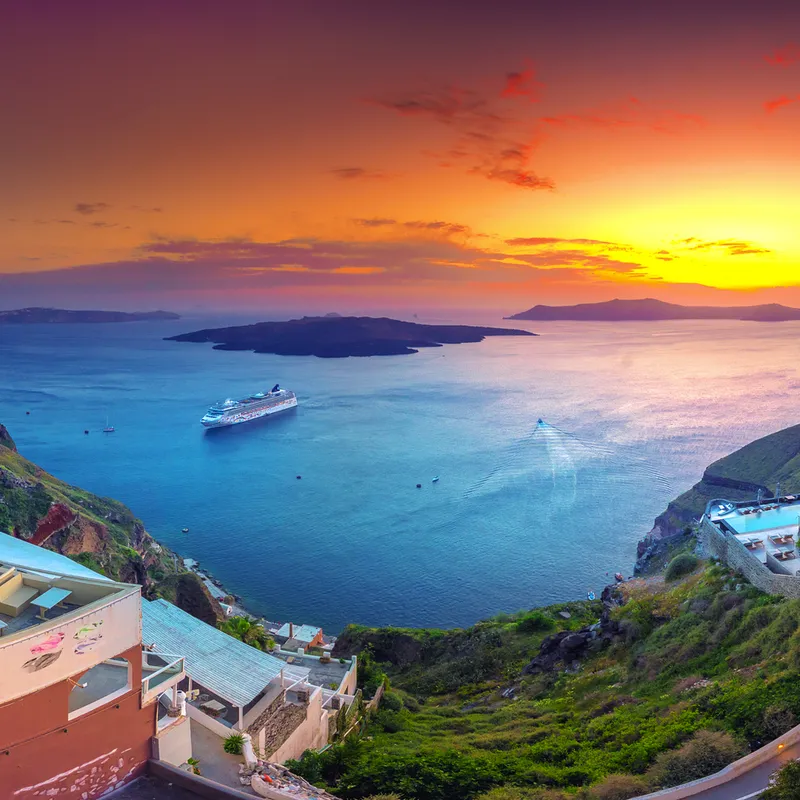 Panoramablick auf Santorin bei Sonnenuntergang mit Blick auf das Meer und ein Kreuzfahrtschiff.