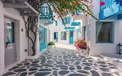 Gepflasterte Gasse mit weißen Häusern und blauen Türen in Santorin.