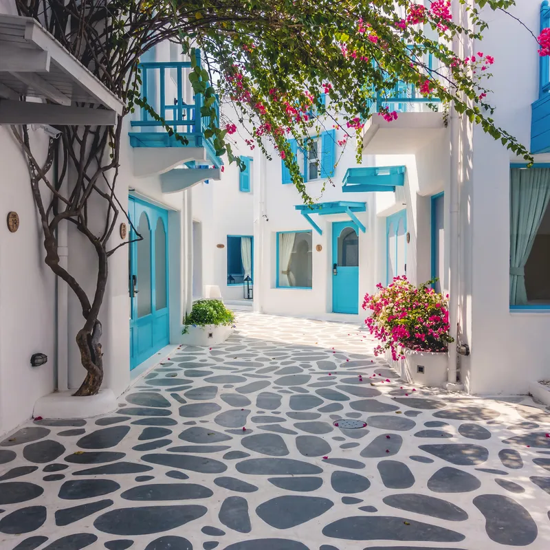 Gepflasterte Gasse mit weißen Häusern und blauen Türen in Santorin.