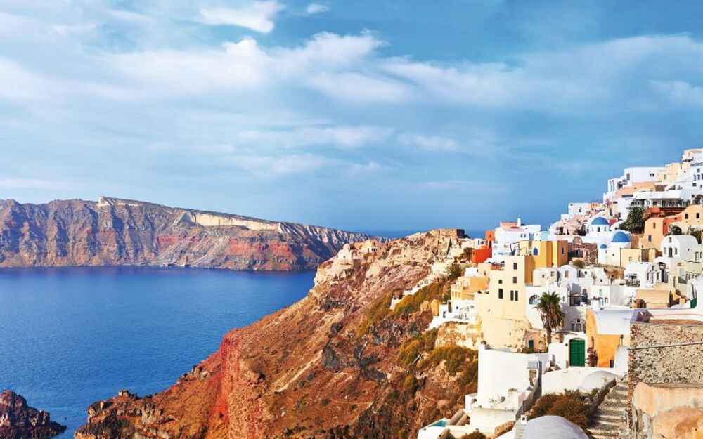 Küstenlandschaft mit weißen Gebäuden und blauen Kuppeln, Santorini, Griechenland.