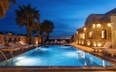 Poolbereich des Iliada Odysseas Resorts bei Abenddämmerung auf Santorin.
