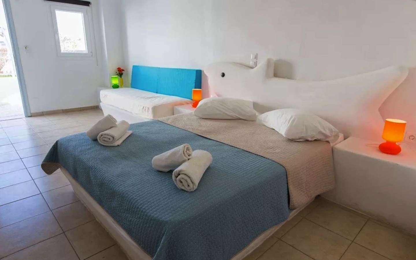 Doppelbett in hell eingerichtetem Hotelzimmer mit Kingsize-Bett und bunten Lichtern.