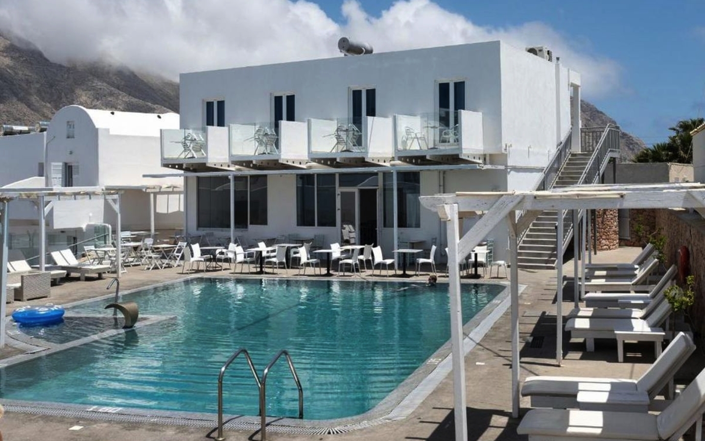 Hotelpool mit Liegestühlen und weißen Gebäuden im Hintergrund.